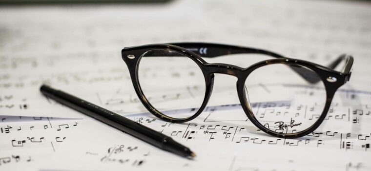 black framed panto-style eyeglasses beside black ballpoint pen